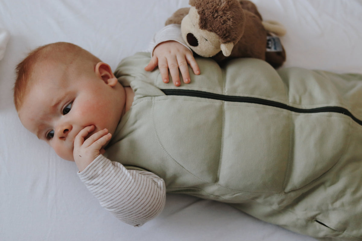 Rolig baby, der hviler i en vægtet sovepose fra BABYDEEPSLEEP